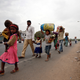 Migrant workers walk with their children as they look out for transport to return to their villages, in Ahmedabad